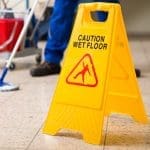 Worker Mopping Floor With Wet Floor Caution Sign